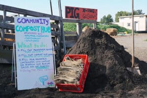 Alameda Post - a photo of a large pile of compost, a box of reusable bags, and an instruction white board