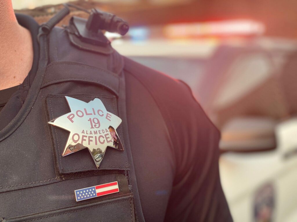 Alameda Post - close up photo of an APD badge and uniform