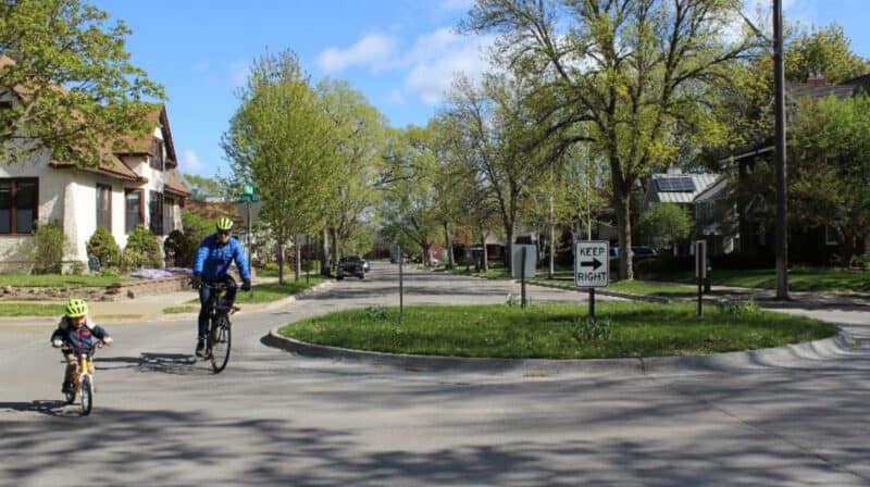 Alameda Post - a parent and child on bikes safely cross a road using a roundabout 