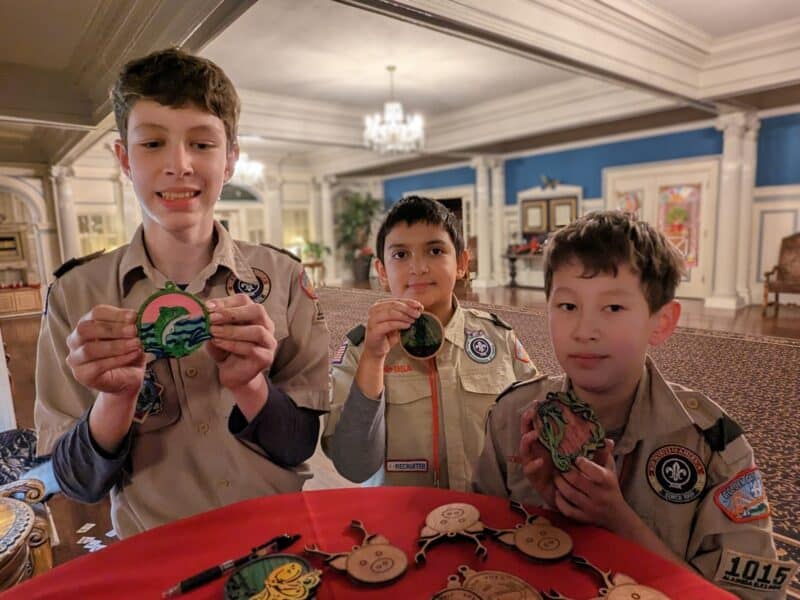 Alameda Post - three Scouts stand in their uniforms posing with laser-cut ornaments 