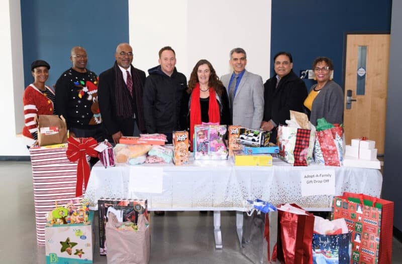 Alameda Post - a group of smiling staff members in front of a table of toys at the Firefighters Toy Drive