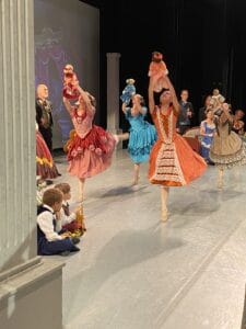 Alameda Post - dancers perform onstage holding up presents that they just received in the ballet