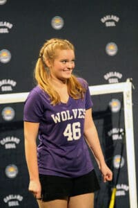 Alameda Post - a soccer player with braids and pigtails wears a purple uniform. They smile and look off to the right