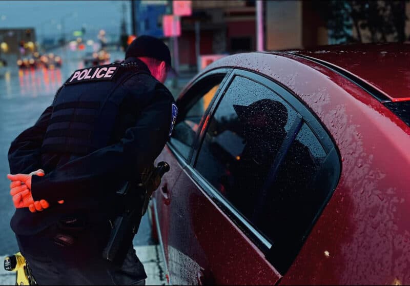 Alameda Post - a photo of a police officer leaning down to talk with someone through an open window on the driver's door of a car