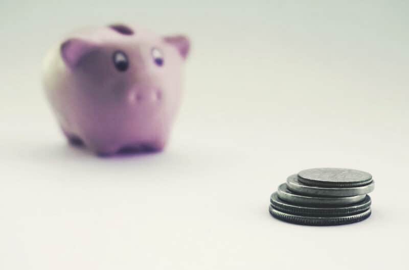 Alameda Post - a piggy bank and a pile of coins representing the options to save or to spend in marriage finances