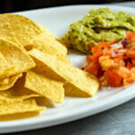 Alameda Post - a plate of tortilla chips with guacamole and salsa