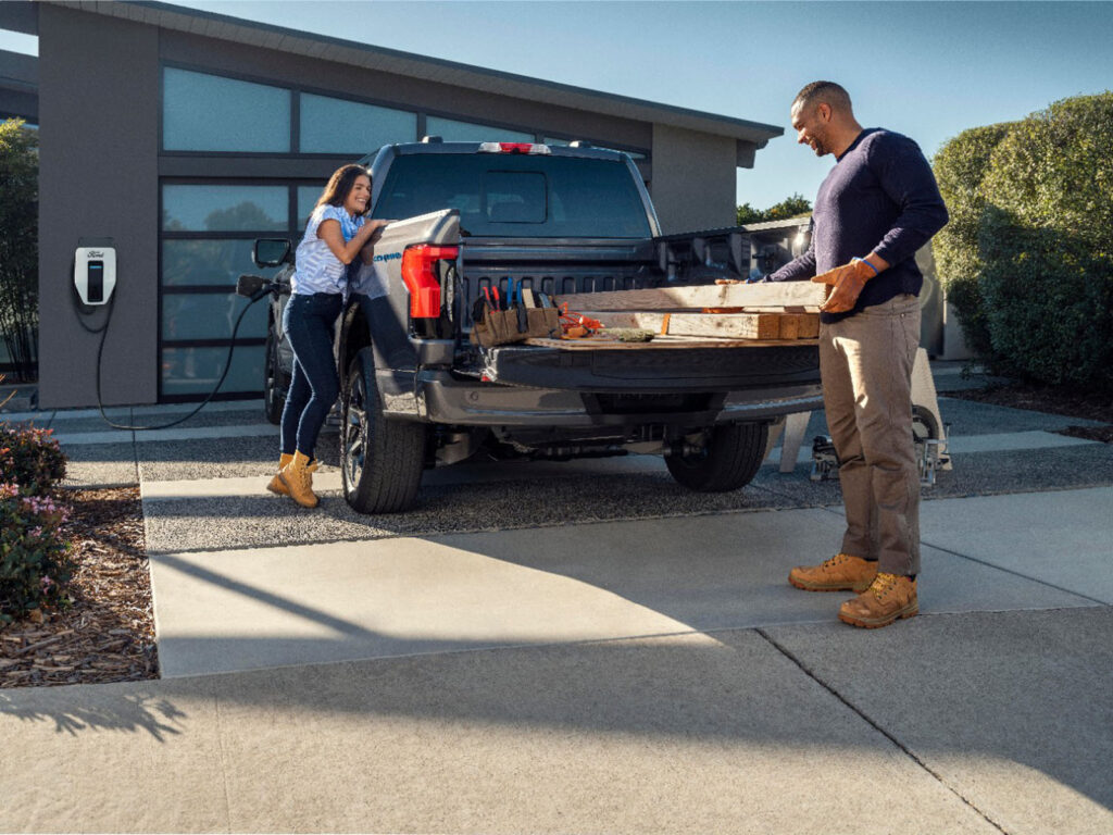 Alameda Post - a couple unloads wood out of a F-150 Lightning as it charges in the driveway