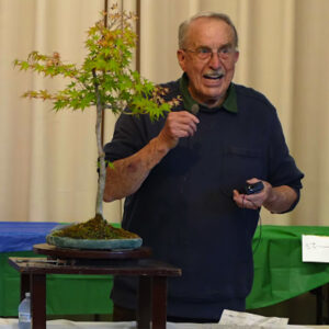 Alameda Post - a man next to a bonsai tree speaking into a microphone