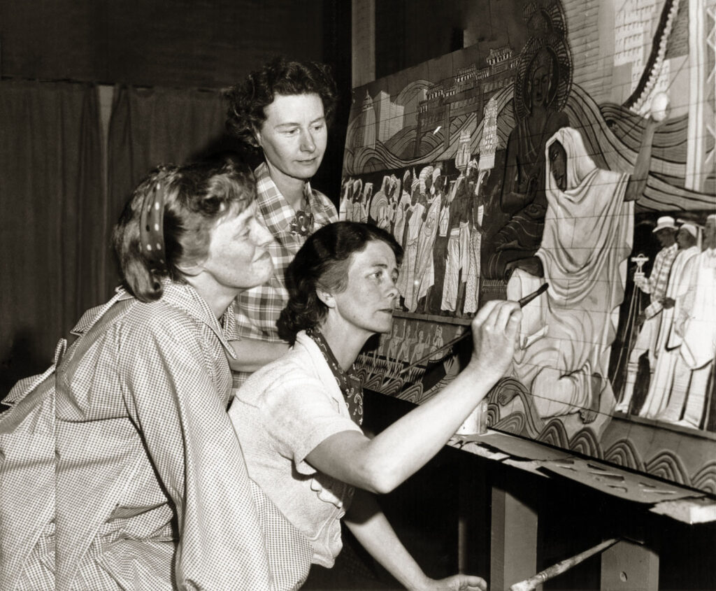 Alameda Post - a black and white photo of the Bruton sisters gathered around a painting while one lifts a paint brush