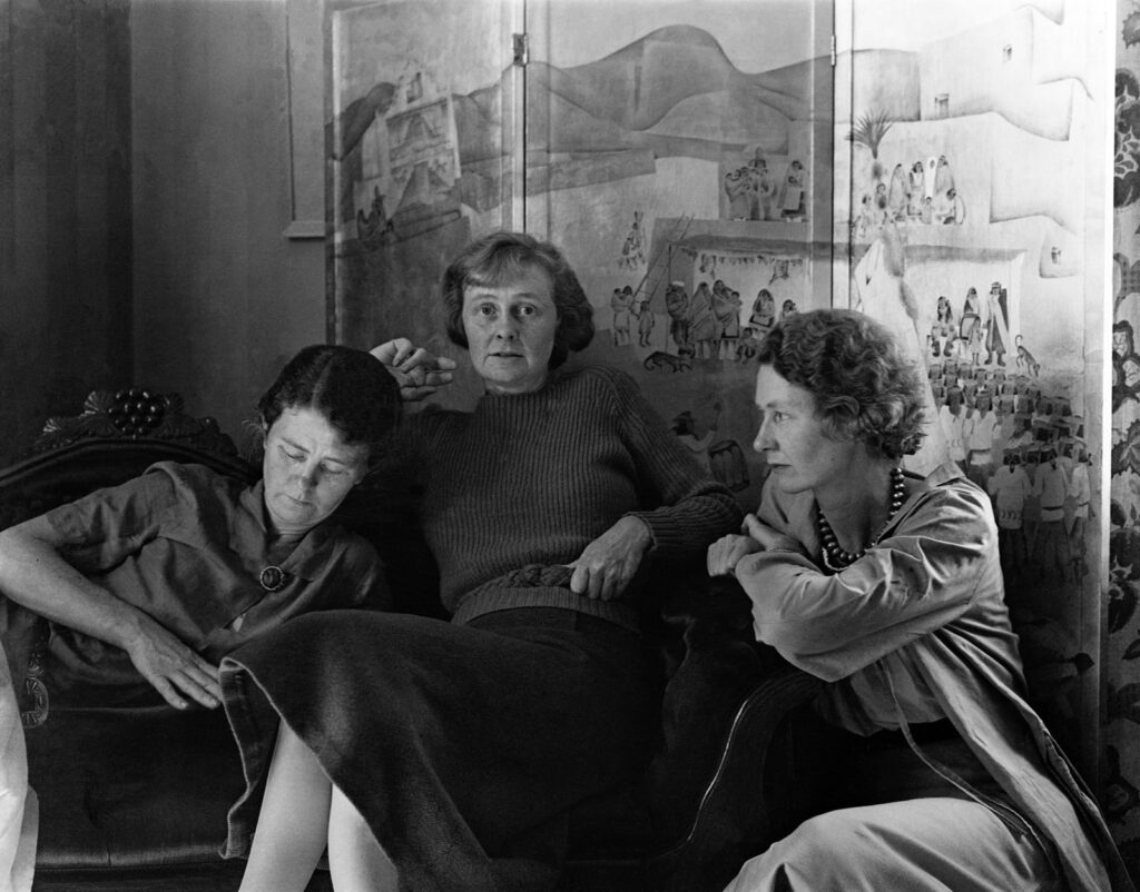 Alameda Post - the Bruton sisters pose for a black and white photo. The are relaxed and seated on and near a nice couch in front of a piece of art. Black and white.