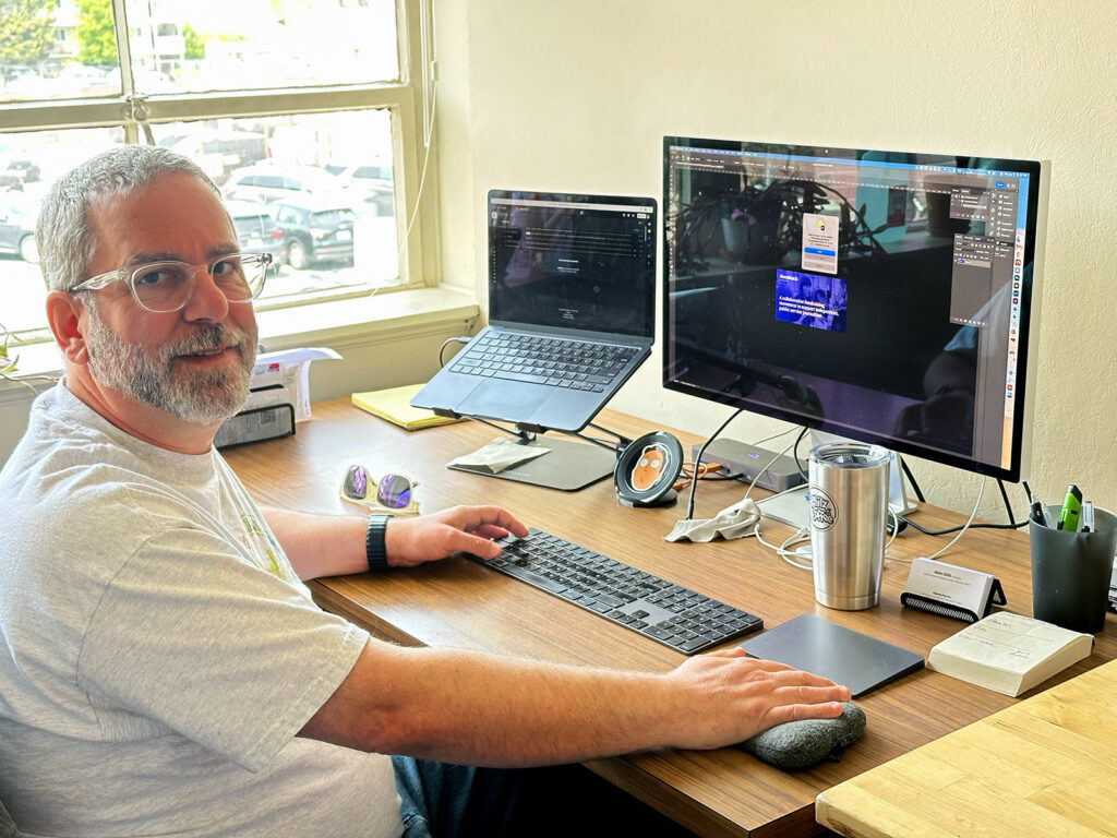 Alameda Post - Adam Gillitt sits at a desk