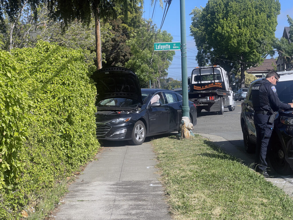 Alameda Post - Bear's-Eye View of Alameda for May 24, 2023 – a Chevy Malibu car with its hood open across a sidewalk apparently after crashing