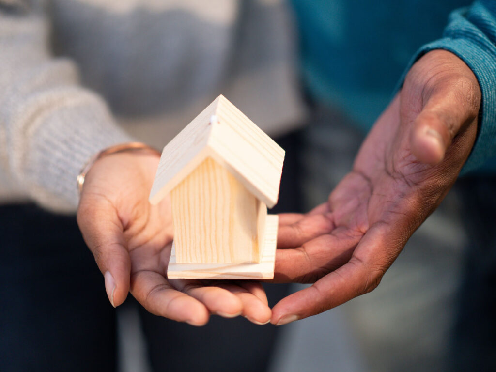 Alameda Post- hands holding a small wooden house