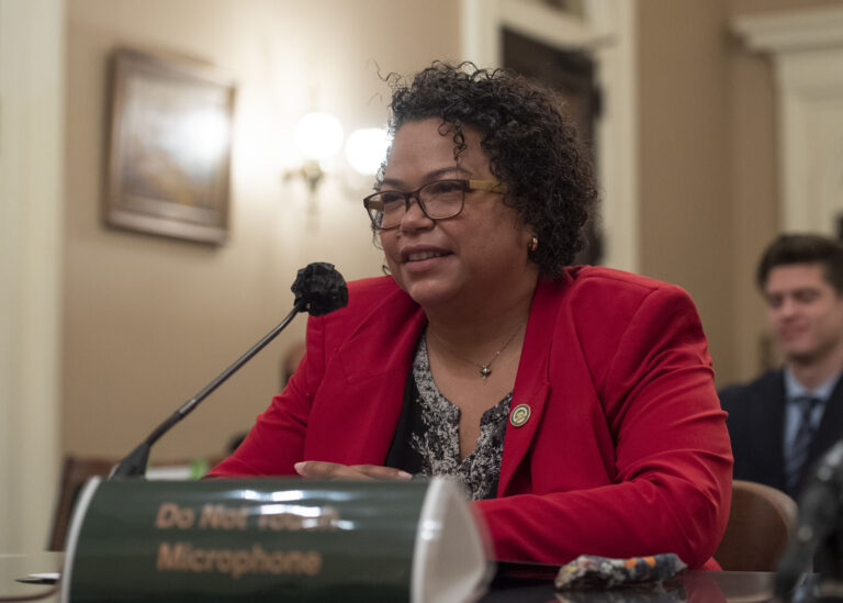 Alameda Post - Mia Bonta speaks into a microphone and wears a brigth red blazer