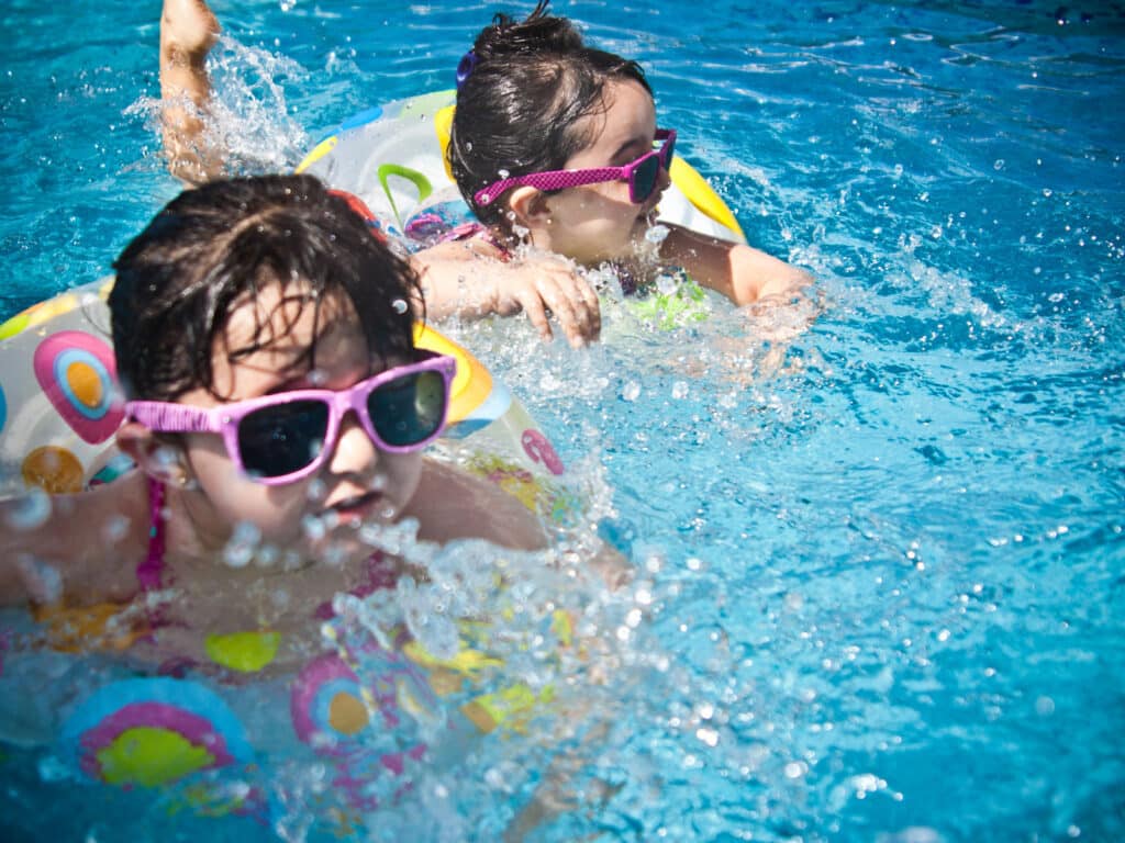 Alameda Post - two kids swim on floaties with sunglasses