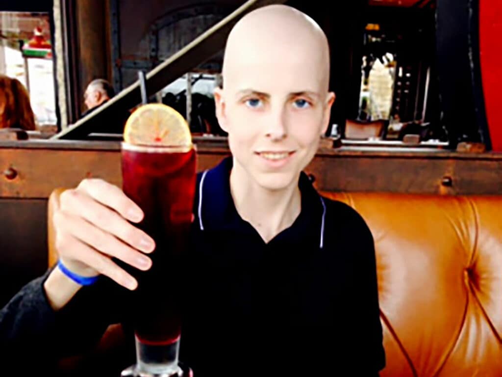 Alameda Post - Pierre Schreyer of Pierre's Birthday Fund holds up a drink and smiles at a restaurant. 