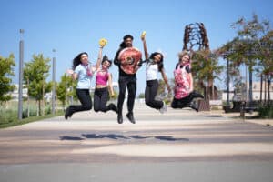 Alameda Post - five people wearing or holding donut merchandise jump in the air and smile