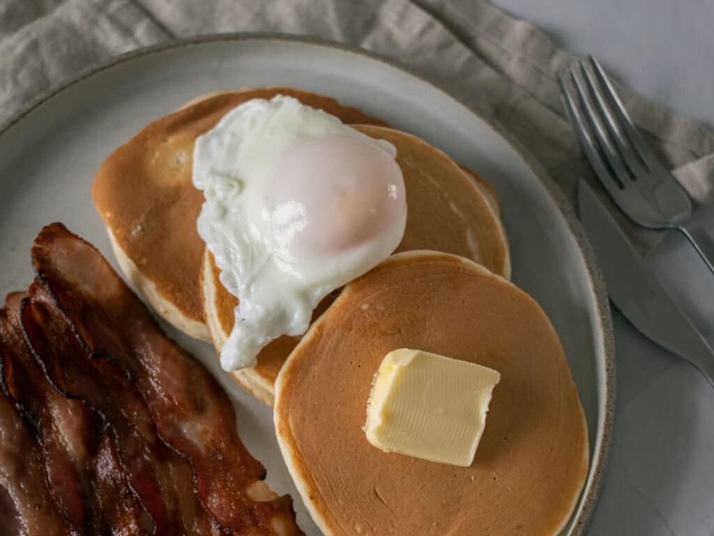 Alameda Post - a poached egg on a pancake next to some bacon