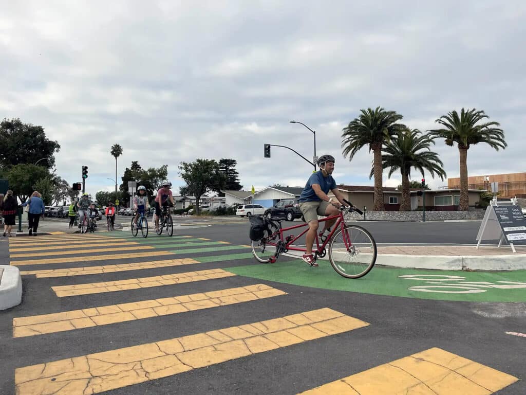 Alameda Post - people ride bikes across a crosswalk