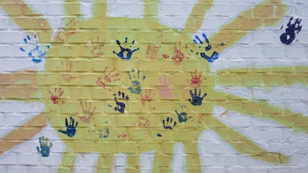 Alameda Post - a sun painted on a wall with handprints