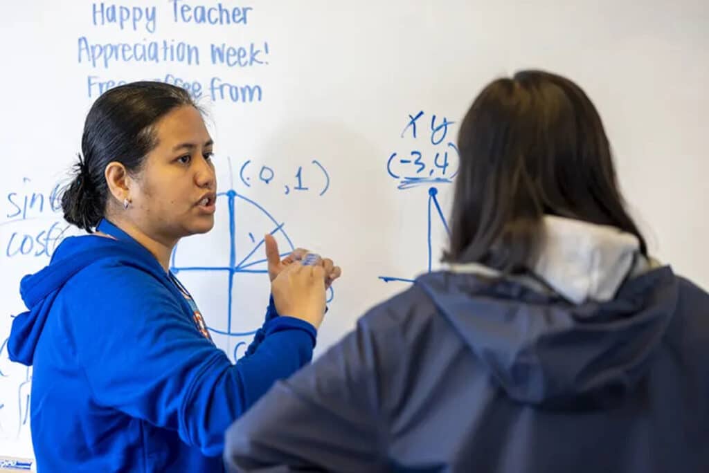 Alameda Post - a Saint Joseph Notre Dam High School student stands at the board with a marker doing math