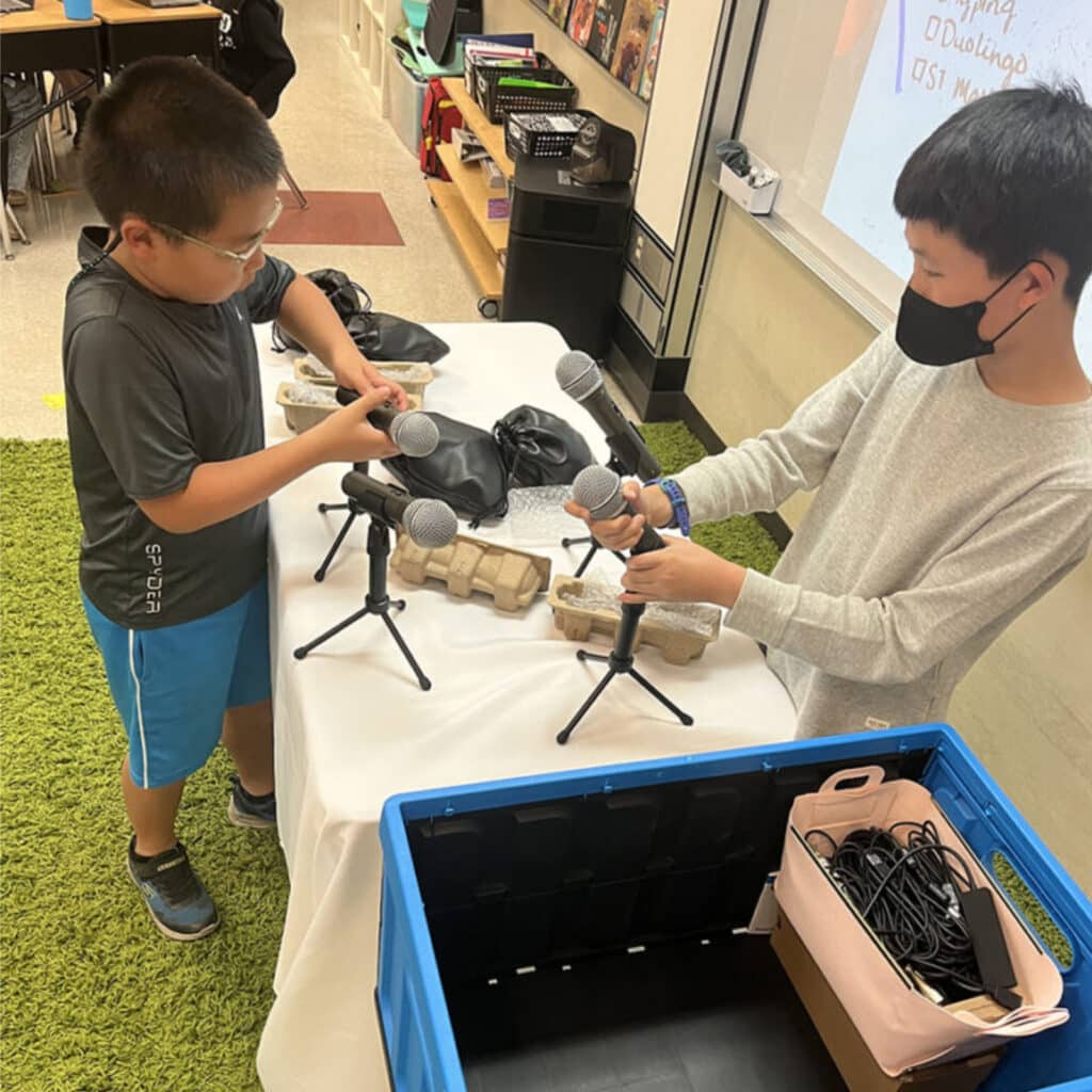 Alameda Post - two children set up microphones and equipment on a podcast table