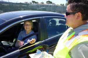 Alameda Post - a person in a car smiles while filling out a clipboard
