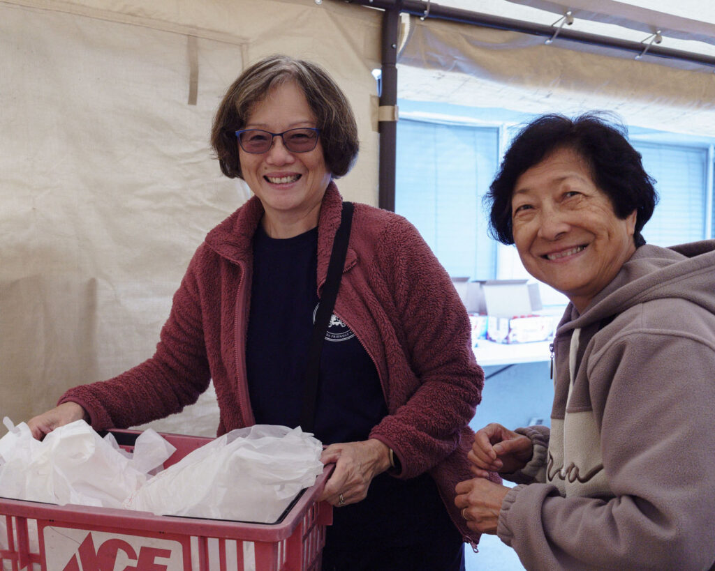 Alameda Post - two volunteers hold food and smile