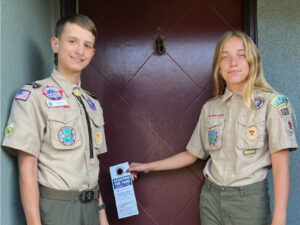 Alameda Post - two Alameda Scouts stand next to a door with doorhangers that announce the food drive