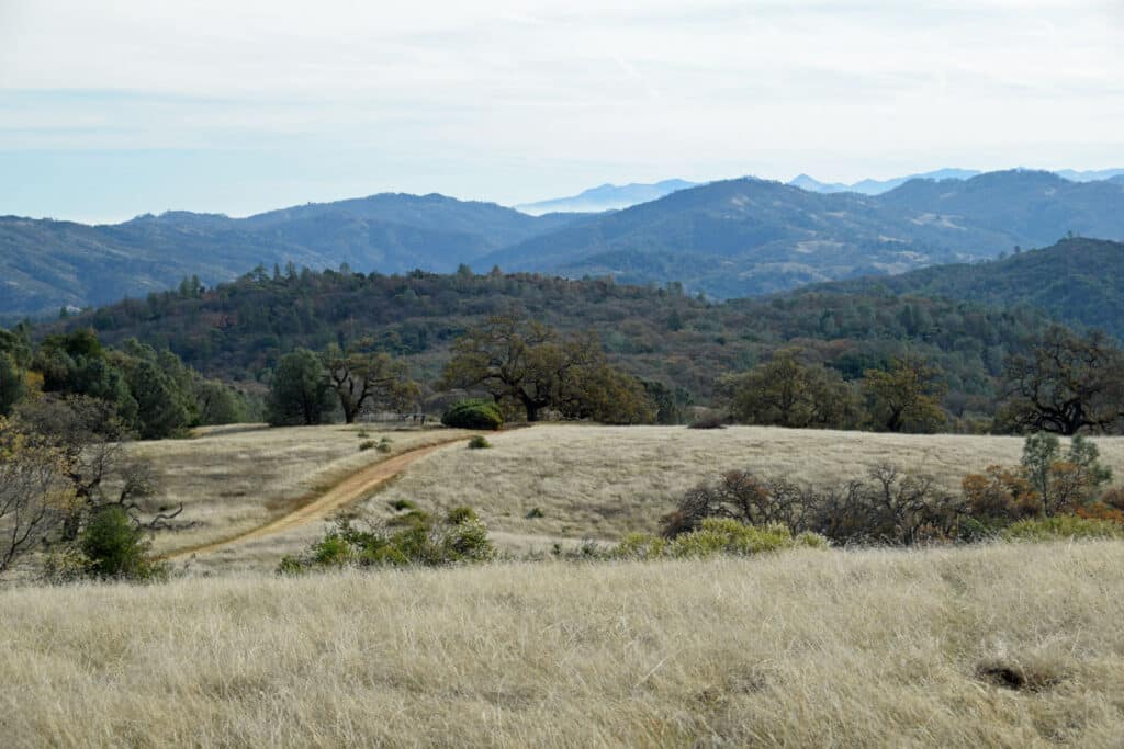 Alameda Post - an old dirt road that goes in to the distance. Hills decorate the landscape. 