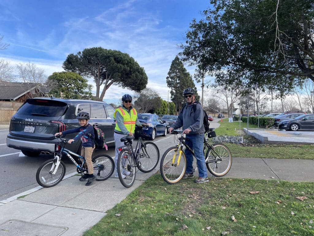 Alameda Post - two adults and one child on their bikes ready to leave Bay Farm School area
