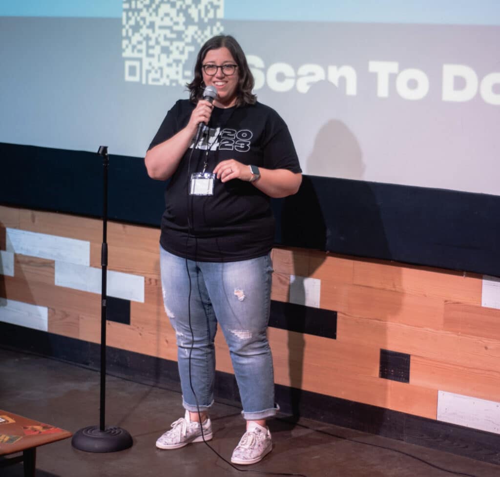 Alameda Post - Heather Decker holds a microphone and speaks onstage