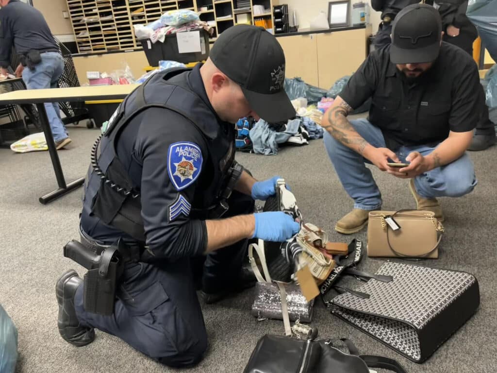 Alameda Post - an APD officer goes through handbags with the tags still on that after APD recovers stolen goods