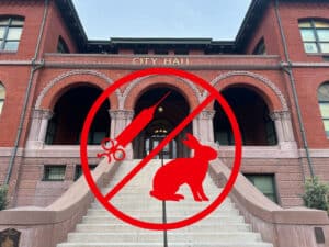 Alameda Post - City Hall with a circle and slash of a bunny and a syringe, indicating no animal testing
