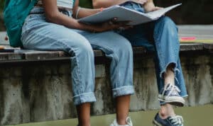 Alameda Post - school age kids sit on a ledge with binders open