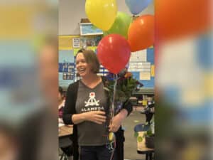 Alameda Post - Emily Pieri smiles and holds balloons in a classroom