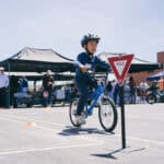 Alameda Post - a young child on a bike and Alameda Bike Festival 2024 rides next to a small yield sign at his height
