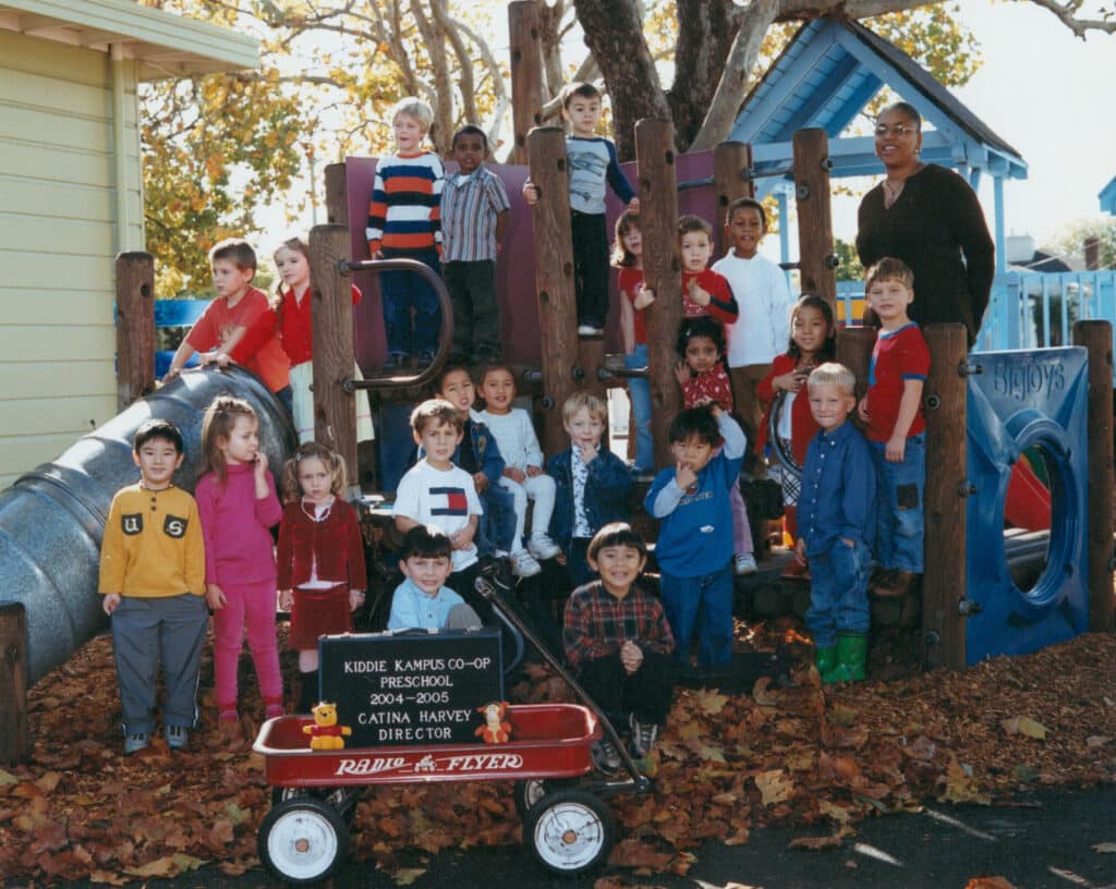 Alameda Post - a slightly dated photo of a group of children. A sign in front of the crowd of children sits on a red wagon and reads "Kiddie Kampus Co-op Preschool 2004-2005 Catina Harvey Director"