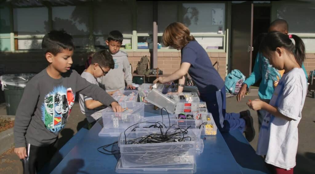 Alameda Post - kids surround a table at summer camp. 