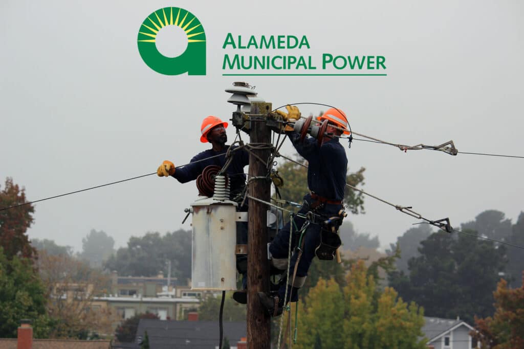 Alameda Post - Alameda Municipal Power (AMP) line workers atop a utility pole wearing orange helmets on an overcast day with the Alameda Municipal Power logo superimposed on the image.