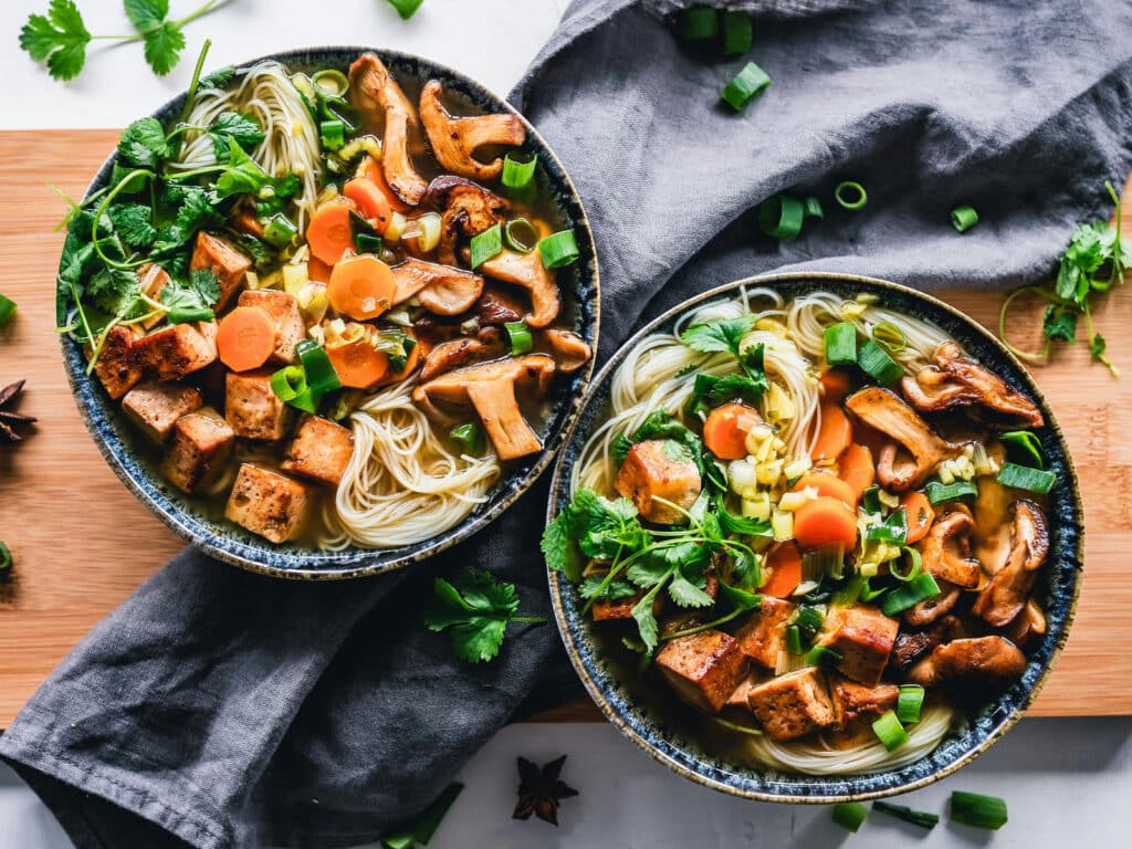 Alameda Post - a bowl of plant-based soup with mushrooms, tofu, noodles, and veggies