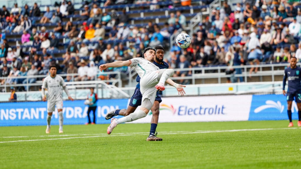 Alameda Post - Two soccer players vie for the ball. 