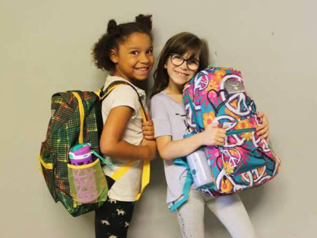 Alameda Post - two school children stand and smile, holding backpacks