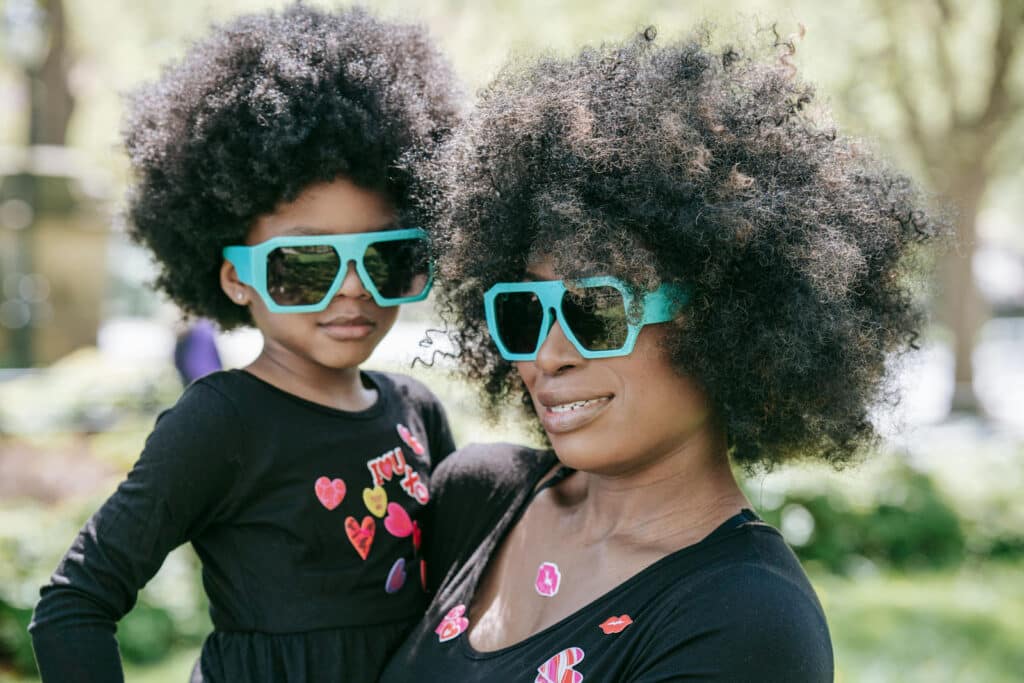 Alameda Post - a parent holds their child. They both wear matching sunglasses