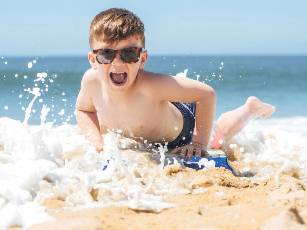 Alameda Post - a child at the beach plays in the waves and wears sunglasses