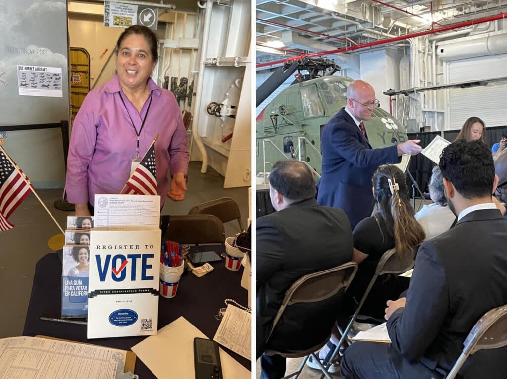 Alameda Post - a woman smiles behind a table which is covered with materials to register to vote, and a man passes out papers to a crowd