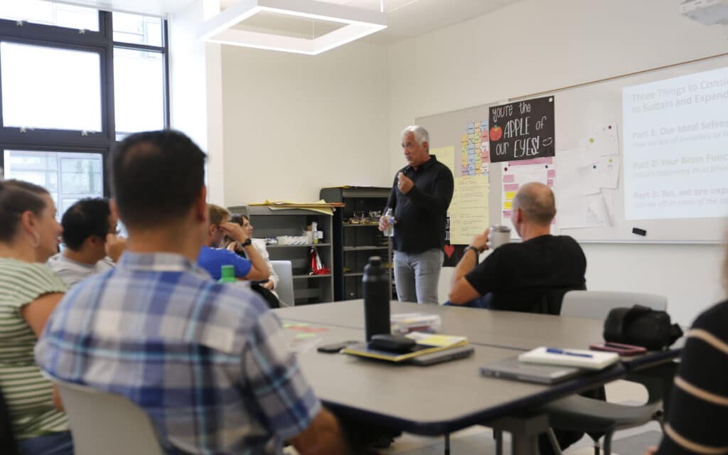 Alameda Post -AUSD Superintendent Scuderi stands at the front of a room and gives a presentation to adults