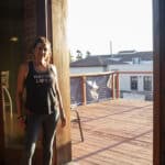 Alameda Post - a woman in workout gear stands next to an open door leading onto a deck
