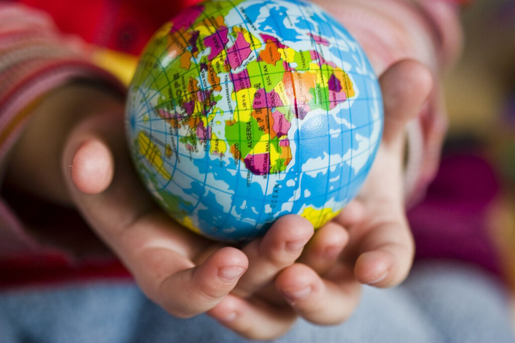 Alameda Post - a pair of young hands hold a globe