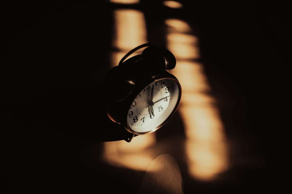 Alameda Post - an old fashioned analog alarm clock in shadows